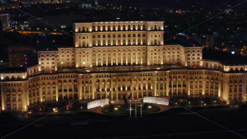Video - Aerial drone view of illuminated Palace of the Parliament in Bucharest downtown in the evening. Multiple districts around. Romania