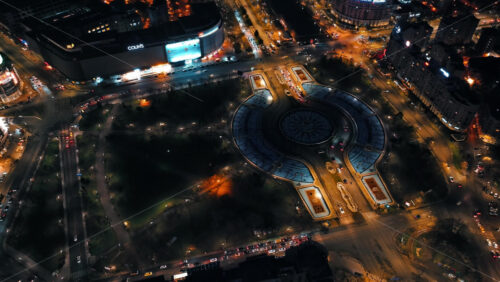 Video - Bucharest, Romania - March 03, 2024: Aerial drone view of a downtown roundabout intersection with moving traffic. Illuminated city in the night