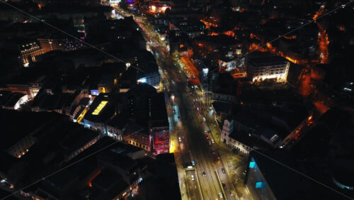 Video - Bucharest, Romania - March 03, 2024: Aerial drone view of illuminated cityscape in the night. Moving traffic on the road