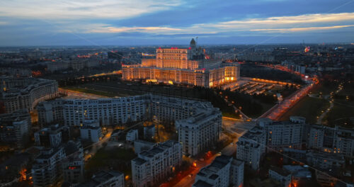 Video - Aerial drone view of illuminated Palace of the Parliament in Bucharest downtown in the evening. Multiple districts around. Romania