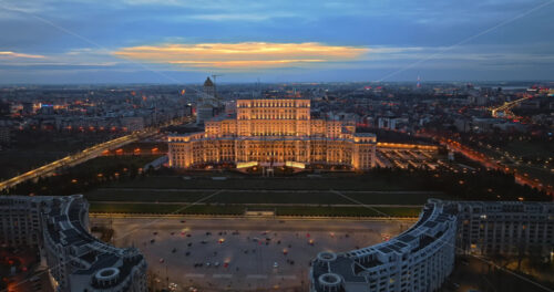 Video - Aerial drone view of illuminated Palace of the Parliament in Bucharest downtown in the evening. Multiple districts around. Romania
