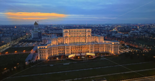 Video - Aerial drone view of illuminated Palace of the Parliament in Bucharest downtown in the evening. Multiple districts around. Romania