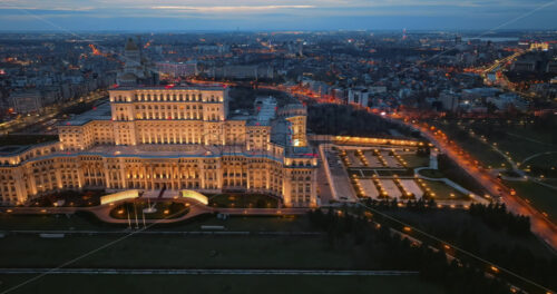 Video - Aerial drone view of illuminated Palace of the Parliament in Bucharest downtown in the evening. Multiple districts around. Romania