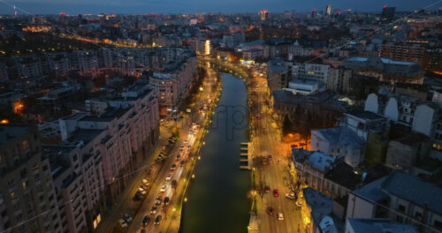 Video - Aerial drone view of Dambovita river in the evening. Illuminated Bucharest city. Blue hour. Romania