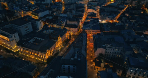 Video - Aerial drone view of walking people among old historical buildings and commercial shops in the old town in the evening. Blue hour in Bucharest, Romania