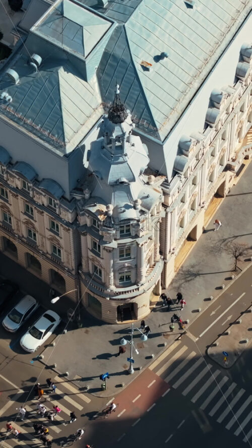 Video - Vertical aerial drone top view of a downtown old historical building in the sunlight. Moving traffic in Bucharest, Romania