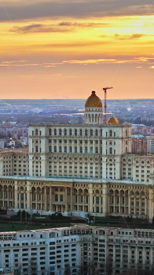 Video - Vertical aerial drone view of Palace of the Parliament in Bucharest downtown at sunset. Multiple districts around, Romania