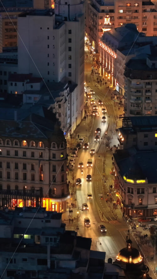 Video - Vertical aerial drone view of illuminated Bucharest city in the evening. Moving traffic. Blue hour, Romania