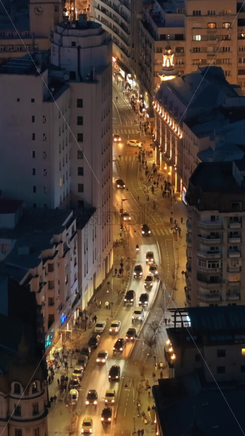 Video - Vertical aerial drone view of illuminated Bucharest city in the evening. Moving traffic. Blue hour, Romania