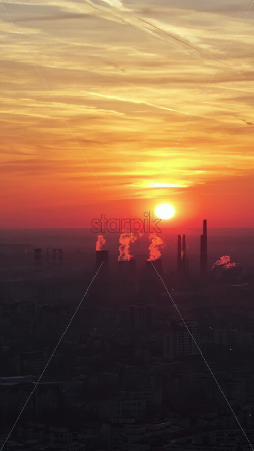 Video - Vertical aerial drone view of thermal power stations in Bucharest at sunset. Red sun. Romania