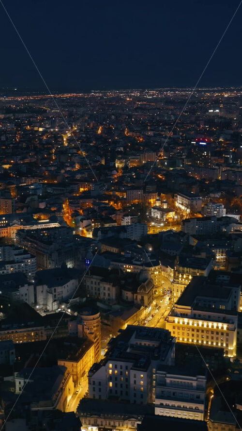 Video - Vertical aerial drone view of illuminated cityscape in the evening. Blue hour in Bucharest, Romania