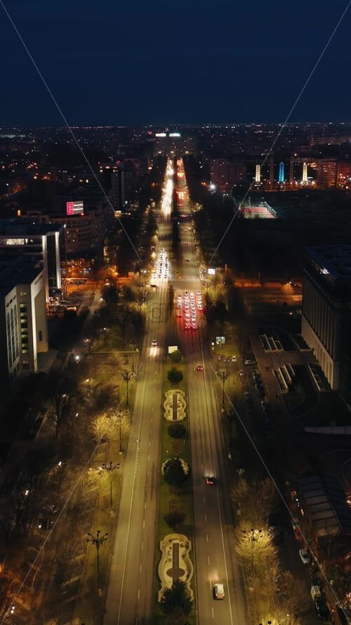Video - Vertical aerial drone view of illuminated cityscape in the night. Moving traffic on the road in Bucharest, Romania