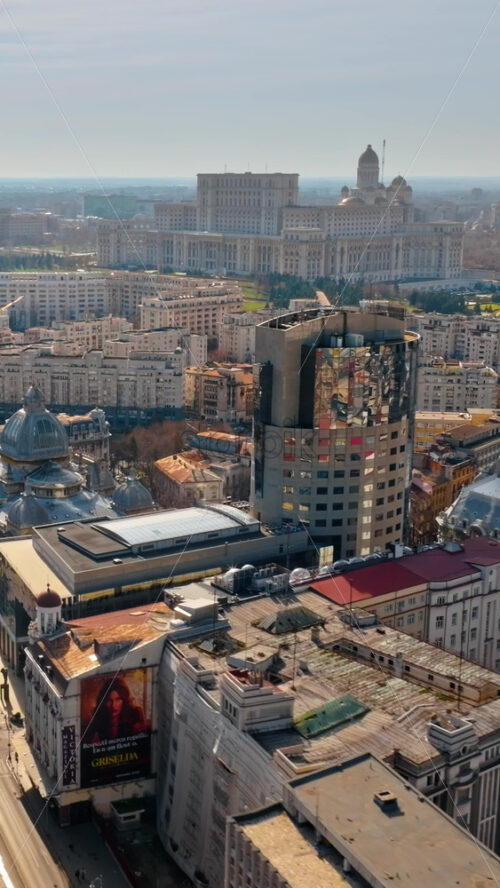 Video - Bucharest, Romania - March 03, 2024: Vertical aerial drone view of the city center with the Palace of Parliament in the background. Sunny day