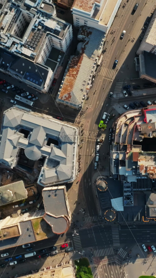 Video - Vertical aerial drone top view of the city center with moving traffic in sunlight. Bucharest, Romania