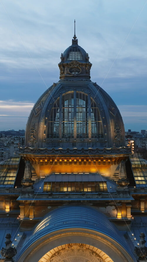 Video - Vertical aerial drone view of the illuminated Palace of the Deposits and Consignments in the evening. Blue hour in Bucharest, Romania