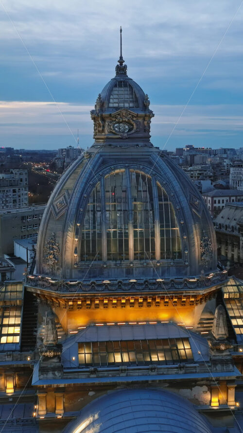 Video - Vertical aerial drone view of the illuminated Palace of the Deposits and Consignments in the evening. Blue hour in Bucharest, Romania