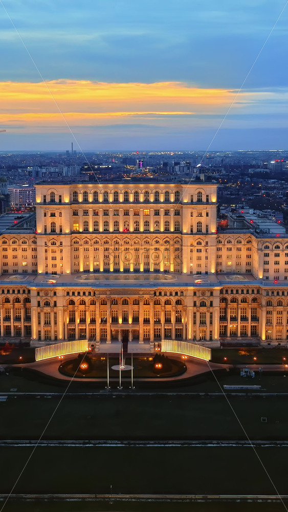 Video - Vertical aerial drone view of illuminated Palace of the Parliament in Bucharest downtown in the evening. Multiple districts around. Romania
