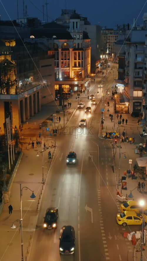 Video - Bucharest, Romania - March 03, 2024: Vertical aerial drone view of illuminated road with moving traffic in the evening. Blue hour