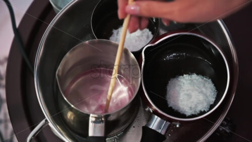 Video - Hand made candles production, female hand mixing melting wax in pots. Slow motion
