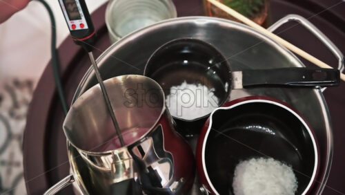 Video - Hand made candles production, female hand mixing melting wax in pots. Slow motion