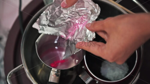 Video - Hand made candles production, female hand adding dye to melting wax in pots. Slow motion