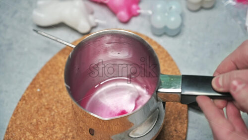Video - Hand made candles production, female hand checking temperature and mixing melting wax in a pot. Slow motion