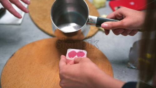 Video - A woman occupied with hand made candles production, pouring melted wax into the mold. Slow motion