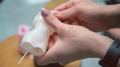 Video - A woman occupied with hand made candles production, preparing a mold for wax. Slow motion