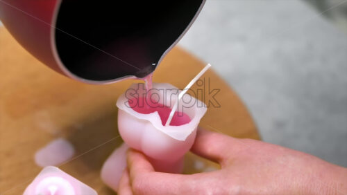 Video - A woman occupied with hand made candles production, pouring melted wax into the mold. Slow motion