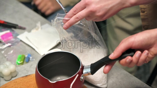 Video - Few women occupied with hand made candles production, adding wax to a pot. Slow motion
