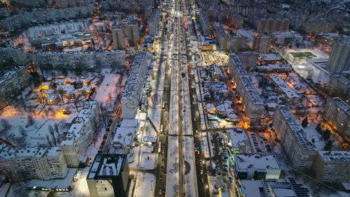 Video - Aerial drone view of Chisinau city covered in snow with moving traffic in the night. Blue hour during winter in Moldova