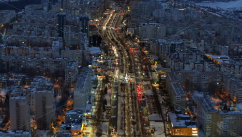Video - Aerial drone view of Chisinau city covered in snow with moving traffic in the night. Blue hour during winter in Moldova