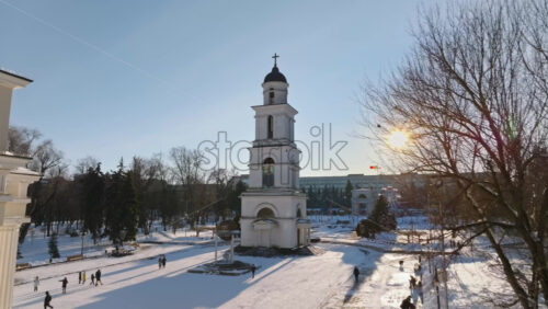 Video - Aerial drone view of the Bell tower of the Metropolitan Cathedral of Christ's Nativity. City center covered in snow at sunset in Chisinau, Moldova