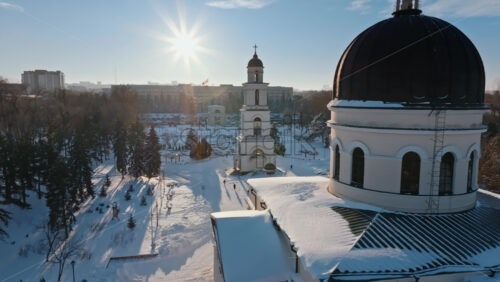 Video - Aerial drone view of the Bell tower of the Metropolitan Cathedral of Christ's Nativity. City center covered in snow at sunset in Chisinau, Moldova
