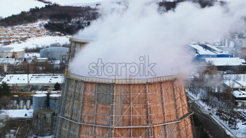 Video - Aerial drone view of a working thermal power station in Chisinau at sunset. City covered in snow. Steam and smoke coming from pipes. Moldova