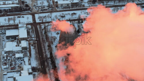 Video - Aerial drone view of a working thermal power station in Chisinau at sunset. City covered in snow. Steam and smoke coming from pipes. Moldova