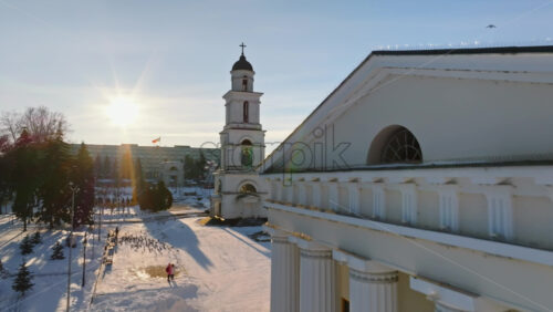 Video - Aerial drone view of the Bell tower of the Metropolitan Cathedral of Christ's Nativity. City center covered in snow at sunset in Chisinau, Moldova