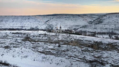 Video - Aerial drone view of the Old Orhei covered in snow at sunrise. Monastery located on a hill in Moldova