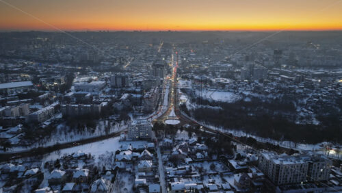Video - Aerial drone view of Chisinau city covered in snow with moving traffic at sunset. Winter in Moldova
