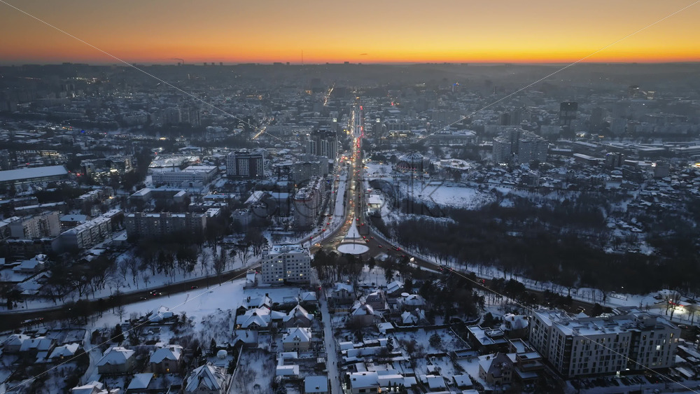 Video - Aerial drone view of Chisinau city covered in snow with moving traffic at sunset. Winter in Moldova