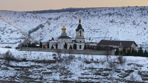 Video - Aerial drone view of the Old Orhei covered in snow at sunrise. Monastery located on a hill in Moldova