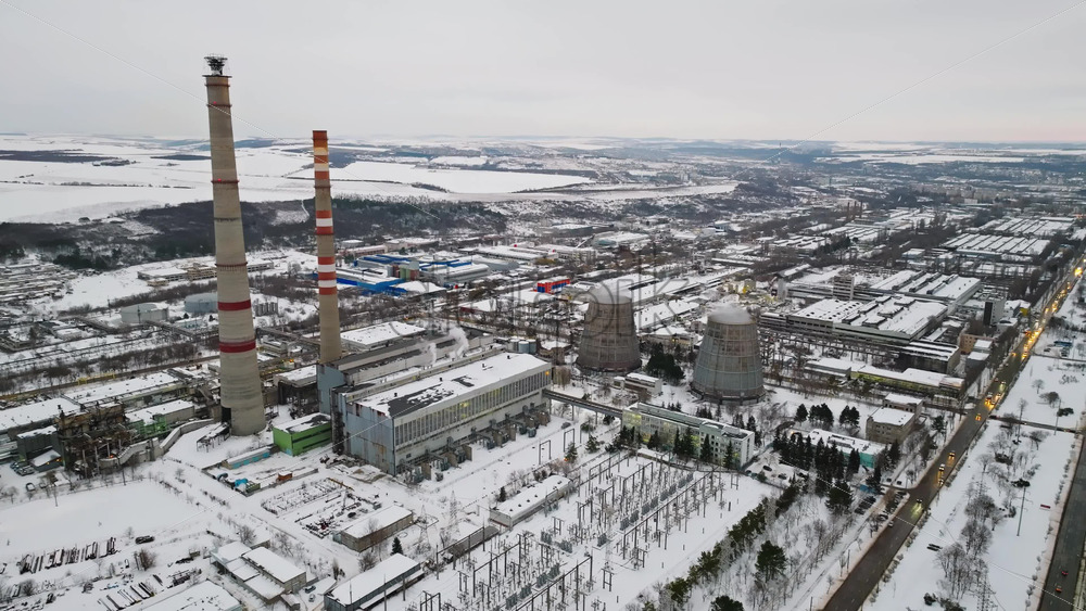 Video - Aerial drone view of a working thermal power station in Chisinau city, covered in snow. Steam and smoke coming from pipes during winter in Moldova