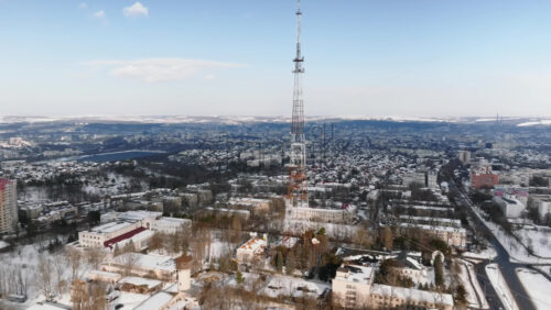 Video - Aerial drone view of the radio transmission tower in the daylight. Ground covered in snow in Chisinau, Moldova