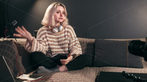 Video - Young content creator blonde talking girl filming herself using a camera on a tripod while recording a vlog. Working from home