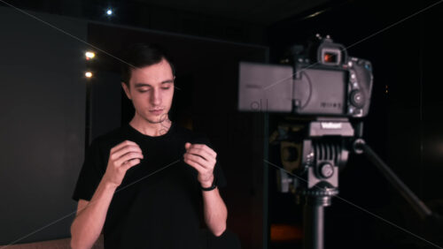 Video - Young content creator talking and gesturing man filming himself using a camera on a tripod while recording a vlog. Working from home