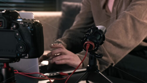 Video - Young content creator girl working on her laptop on the table with camera on a tripod, microphone. Working from home