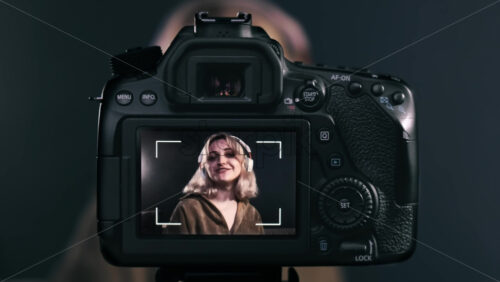 Video - Young content creator blonde talking girl filming herself using a camera on a tripod while recording a vlog. Working from home