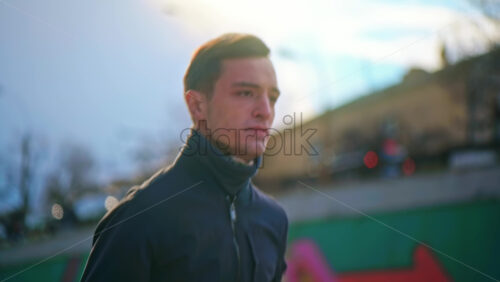 Video - Young focused man running in jacket. Cloudy weather. Slow motion