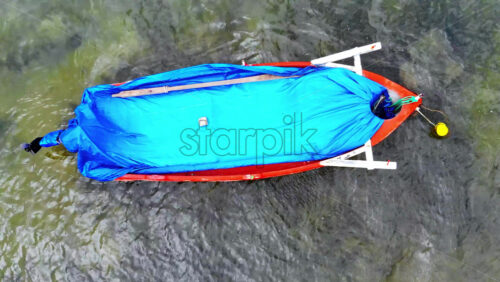 Video - Aerial drone view of a moored boat with blue fabric on it in transparent water of the Aegean sea. Greece