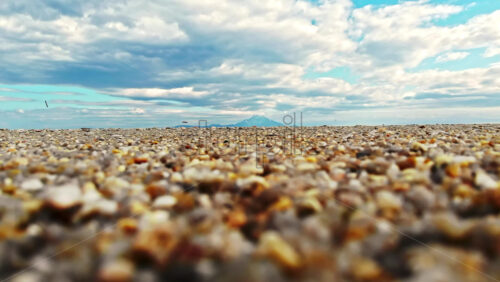 Video - View of a beach from the ground. Sand, clouds, mountain in the distance, Greece